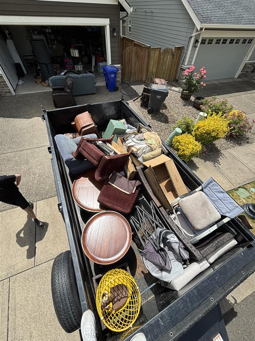 Dump trailer loaded during a full estate cleanout in a Portland-area driveway