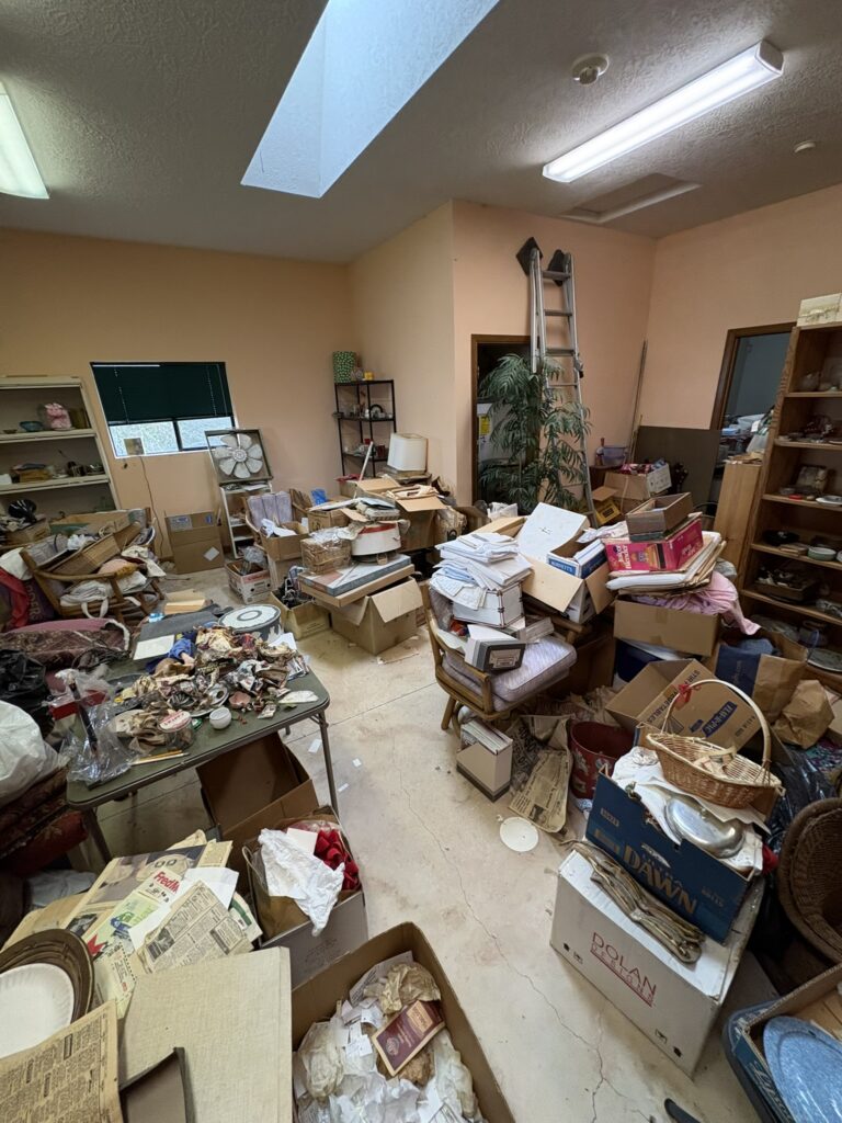 Room packed floor to shelf with boxes, papers and household items before a hoarding cleanout in the Portland area