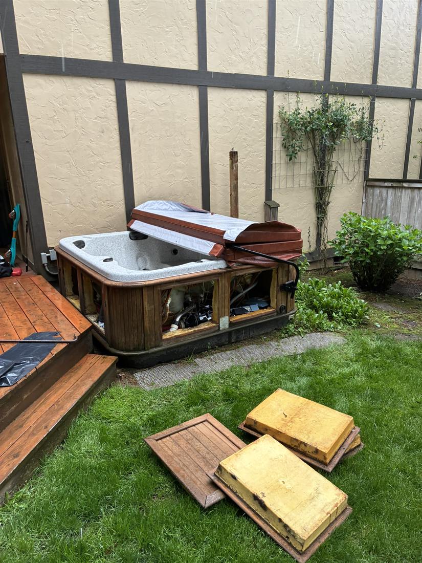 Hot tub being cut down and removed from a backyard patio