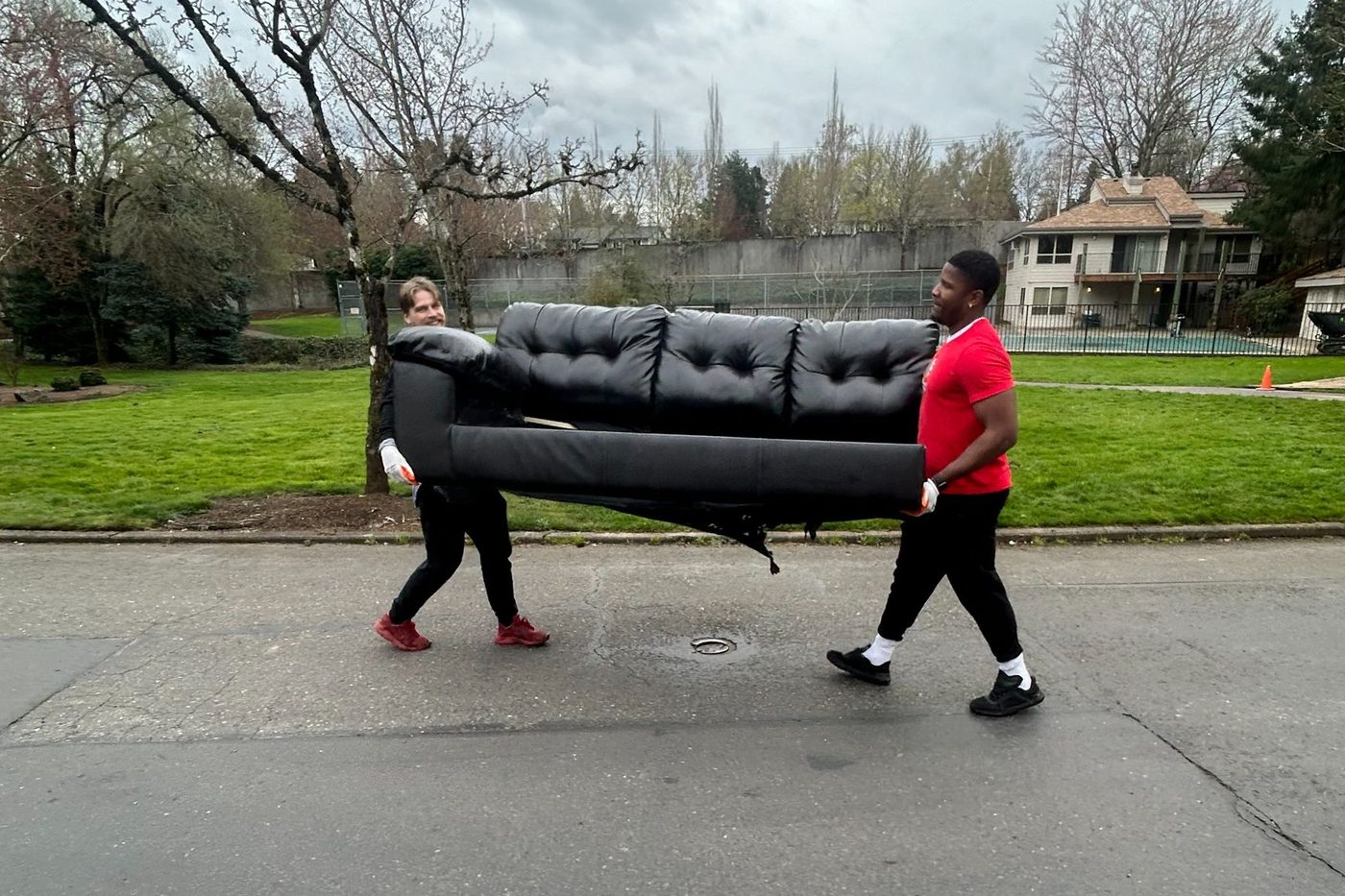 All Oregon Junk Removal crew carrying a leather couch in good condition to be donated