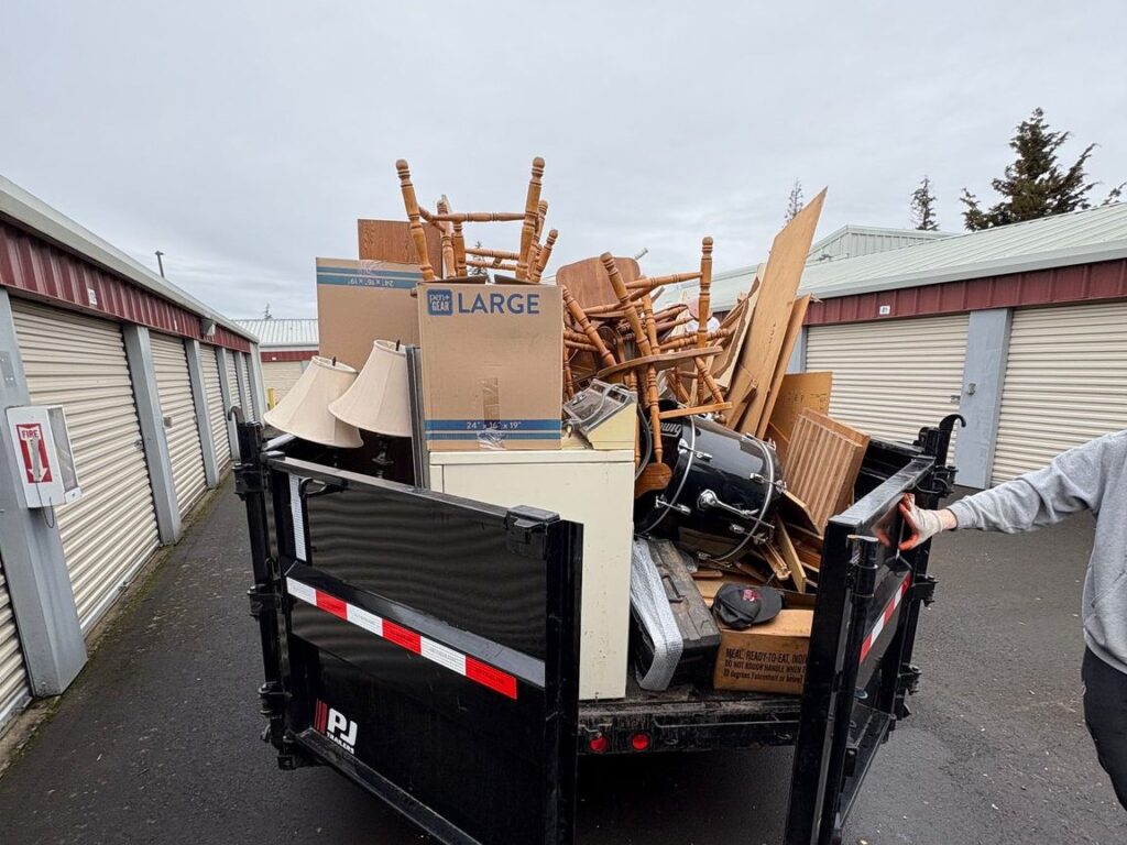 All Oregon Junk Removal dump trailer loaded with furniture, boxes and lamps from a storage unit cleanout